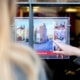 Close up of the back of the head of a blonde long haired person and a young persons hand pointing to property details in a shop window