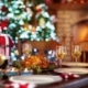 Christmas styled dining table set with plates glasses of white wine tealights Santa decorations and roast chicken with lit Christmas tree and open lit fire in brick fireplace in the background