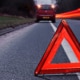 Evening image of car parked at the roadside with red hazard triangle in the foreground