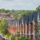 Hillside row of red brick terraced houses tree lined street with parked cars leading down to more rows of terraced rooftops and chimney tops