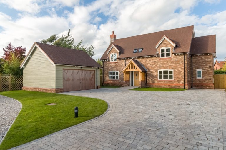 New build cottage style dormer brick property with timbered canopy double detached garage and sweeping block paved driveway