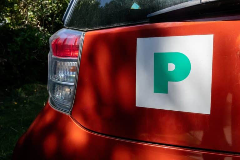 Rear of red orange car with green and white provisional new driver P sticker on boot tailgate next to rear lights