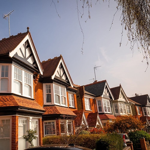 Row of traditional brick and timber Edwardian terraced houses with canopied front doors and box bay windows