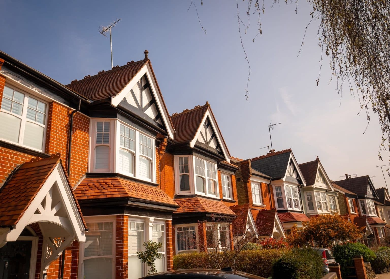 Row of traditional brick and timber Edwardian terraced houses with canopied front doors and box bay windows