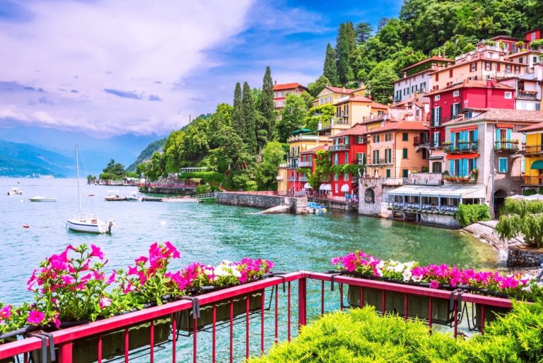 Lake Como Italy summertime image of lakeside multi coloured buildings boats and flower baskets