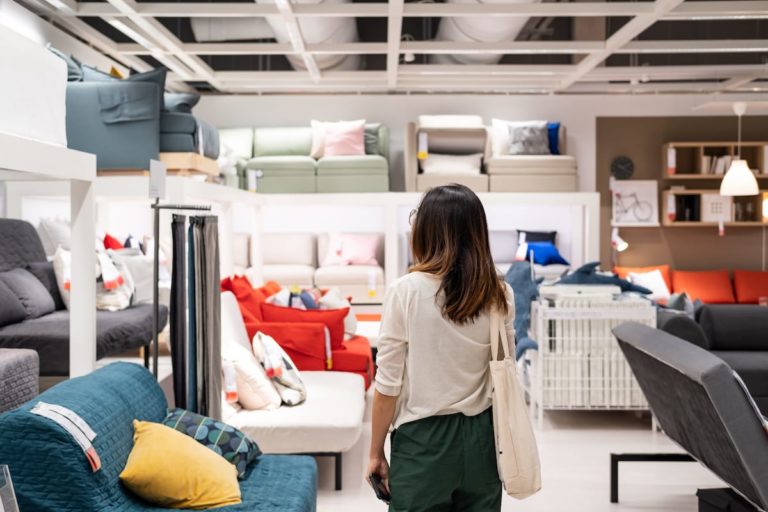 Woman with long brown hair in furniture shop looking at display of sofas and cushions