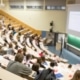 Students in auditorium with lecturer at lecturn in front of large projector screen